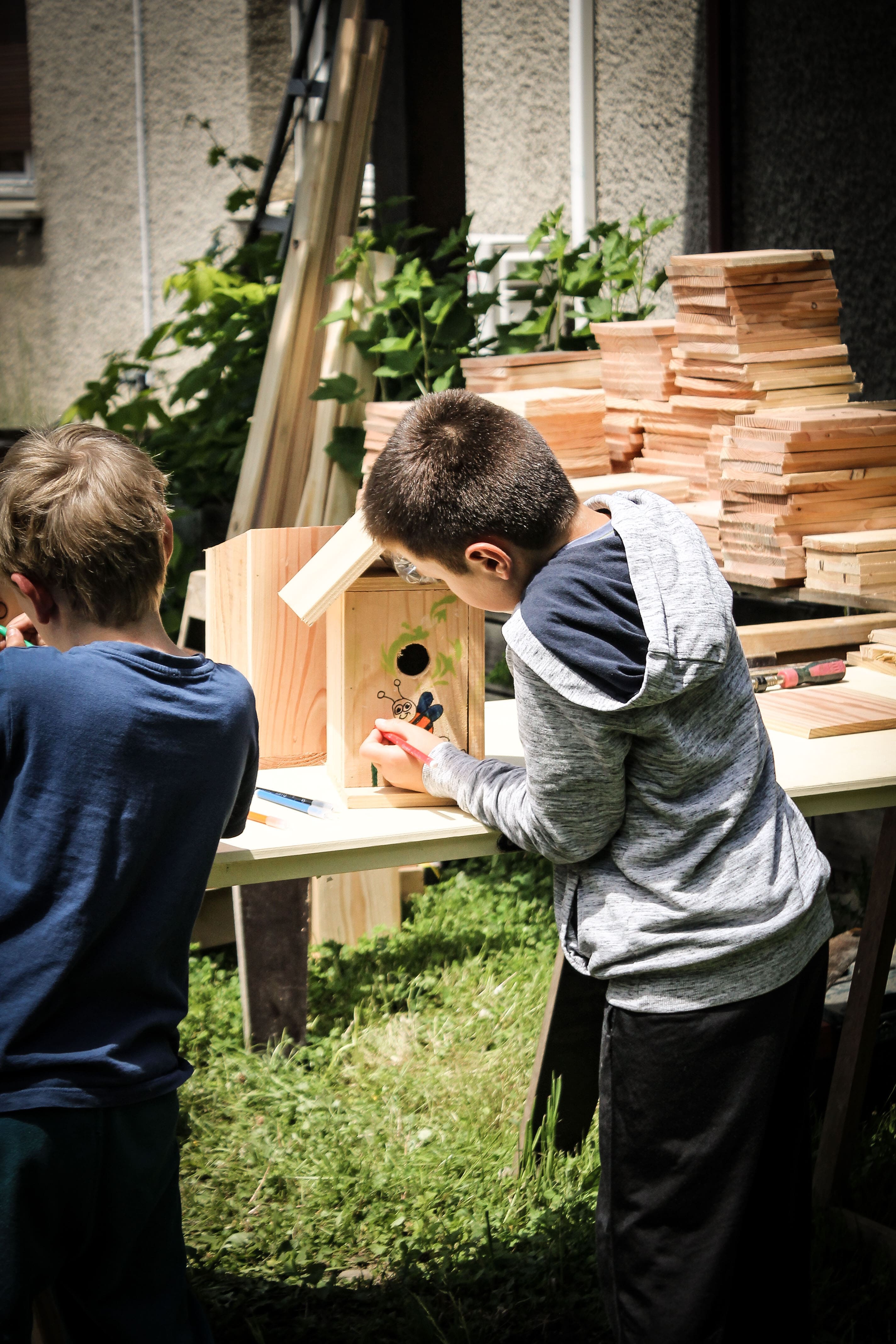 Des enfants en train de peindre sur des abris pour oiseaux